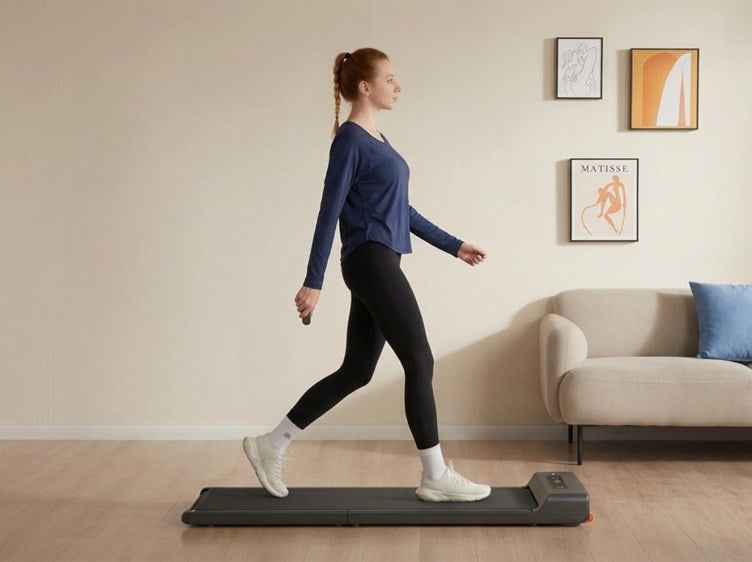 A woman walking on a WalkingPad Z1 walking pad in a calm living room beside a sofa