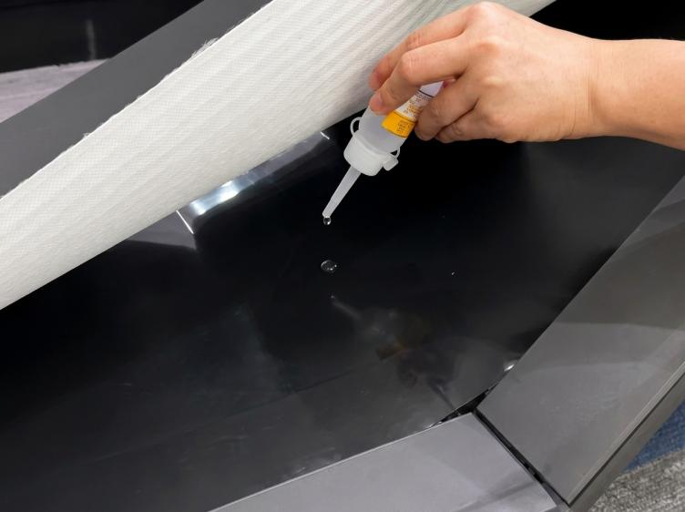 Hand applying lubricant under the belt of a treadmill
